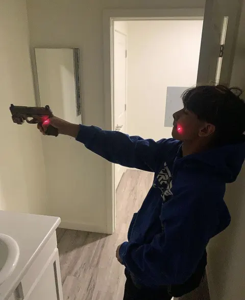 Jovem segurando arma com mira laser