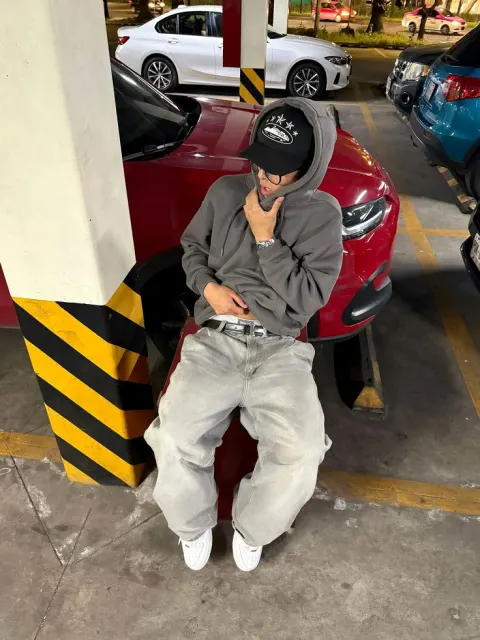 Jovem com moletom cinza em estacionamento