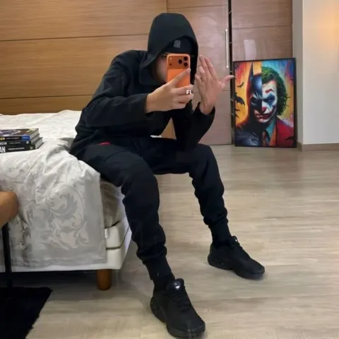 Jovem de moletom preto tirando foto no espelho