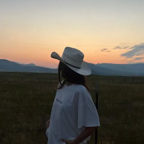 Garota de chapéu no campo ao pôr do sol