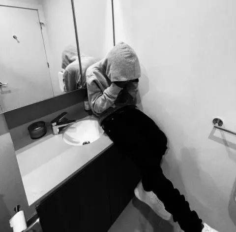 Jovem de moletom no banheiro