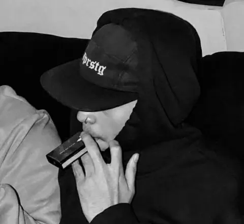 Jovem com boné e capuz em preto e branco