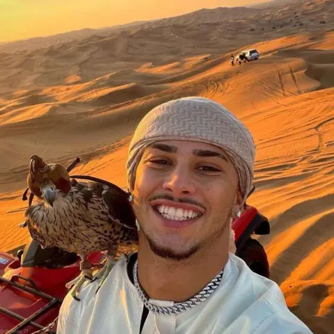 Homem sorrindo com falcão no deserto